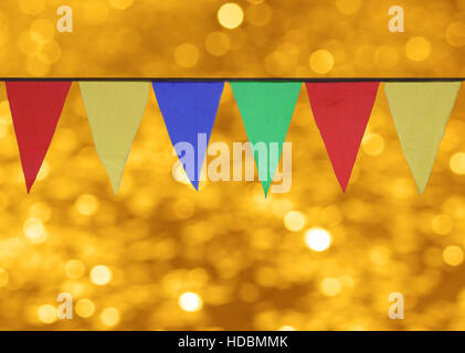 Multi farbige dreieckige Fahnen hängen vor dem Hintergrund der gold Bokeh. Stockfoto