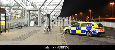 Flughafen Sicherheit UK airport terminal building Essex Polizei Auto und Passagiere vor der Flughafen Stansted kalten Winternacht Stockfoto