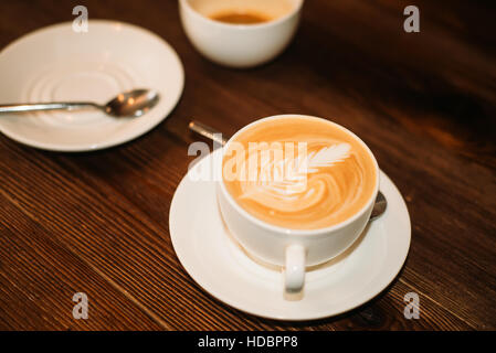 Closeup zwei Tassen Kaffee, Teller und Löffel auf Holztisch. Stockfoto