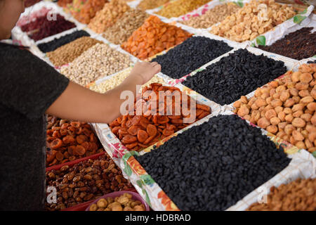 Frau, die Auswahl von getrockneten Früchten und Nüssen auf dem Display am Zentralmarkt Schymkent Kasachstan Stockfoto