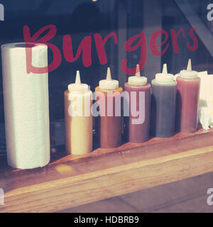 Reihe von Saucen im Fenster von einem Burger-Restaurant Stockfoto