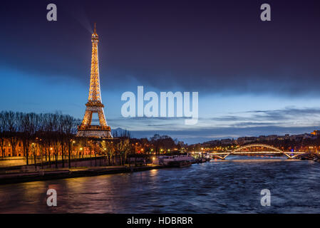 Der Eiffelturm in der Dämmerung mit den Banken des Flusses Seine und die Passerelle Debilly beleuchtet. Paris, Frankreich Stockfoto