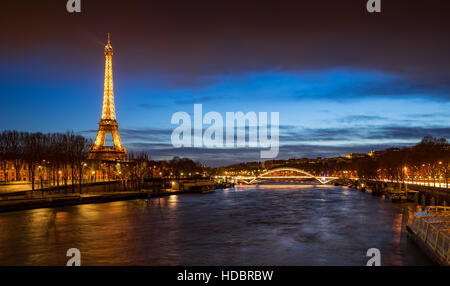 Der Eiffelturm in der Dämmerung mit den Ufern des Flusses Seine und die Passerelle Debilly beleuchtet. Paris, Frankreich Stockfoto