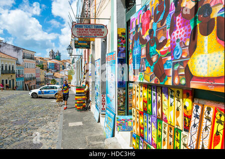SALVADOR, Brasilien - 12. März 2015: Eine Straße Verkäufer steht vor Geschäften mit Afro-brasilianischen Touristen Souvenirs in Pelourinho. Stockfoto