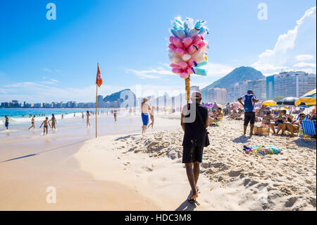 RIO DE JANEIRO - 27. Februar 2016: Brasilianischen Strand Verkäufer Verkauf Baumwolle Zuckerwatte Ansätze Kunden an der Copacabana. Stockfoto