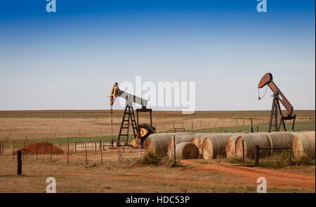 Eine Szene aus ländlichen Oklahoma. Öl Pumpen und Heuballen in der Prärie. Stockfoto
