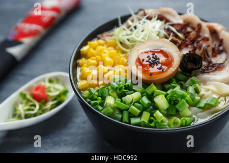 Tonkotsu Ramen, japanische Nudelsuppe mit Schweinebauch, Mais, Frühlingszwiebeln und Nitamago an der Spitze Stockfoto