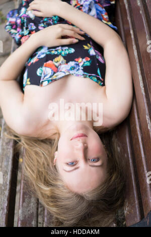 Schöne junge Frau, die Festlegung auf Bank im freien Stockfoto