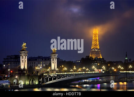 Die Alexandre III Brücke über Seineufer. Im Hintergrund der Eiffel Turm "piercing" die Wolken. Paris, Frankreich. Stockfoto
