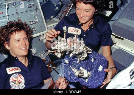 NASA STS - 41G Mission Crew Mitglieder Astronauten, die Kathryn Sullivan (links) und Sally Ride zeigen ihre "Bag of Worms" schlafen Zurückhaltung System Erfindung 6. Oktober 1984 an Bord des Space Shuttle Challenger in der Erdumlaufbahn. Die "Tasche" ist eine schlafende Zurückhaltung und die "Würmer" bestehen aus Federn, Bungee-Seile, Klammern, Clips und Klettverschluss-Streifen um Zurückhaltung zu erleichtern. Stockfoto