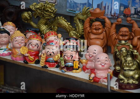 Souvenirs von smiling Buddha und andere chinesischen Schriftzeichen in einem Markt stall in Hong Kong Stockfoto