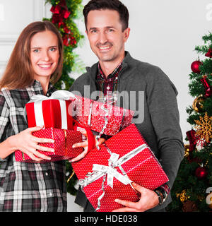 Brautpaar mit Weihnachtsgeschenken in der Nähe von geschmückten Baum Stockfoto