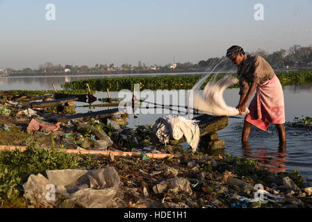 Eine indische Wäscher eine lokale Wäsche waschen von Kleidung am Ufer eines Sees in Muzaffarpur, Indien. Stockfoto