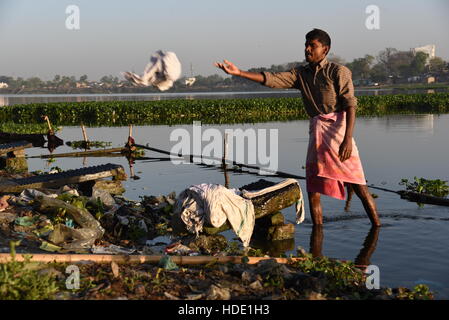 Eine indische Wäscher eine lokale Wäsche waschen von Kleidung am Ufer eines Sees in Muzaffarpur, Indien. Stockfoto