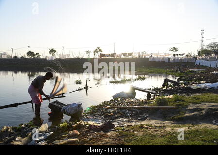 Eine indische Wäscher eine lokale Wäsche waschen von Kleidung am Ufer eines Sees in Muzaffarpur, Indien. Stockfoto