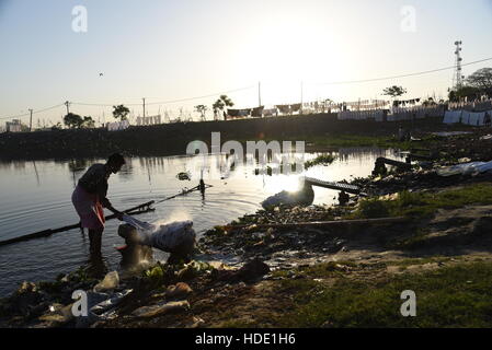 Eine indische Wäscher eine lokale Wäsche waschen von Kleidung am Ufer eines Sees in Muzaffarpur, Indien. Stockfoto