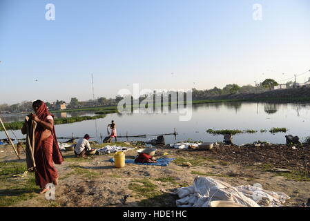 Eine indische Wäscher eine lokale Wäsche waschen von Kleidung am Ufer eines Sees in Muzaffarpur, Indien. Stockfoto