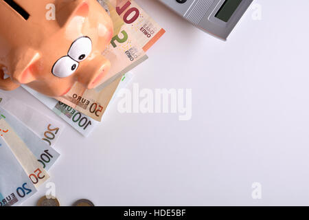 Konzept-Einsparungen und Buchhaltung mit Sparschwein und gestapelten Münzen und Rechnungen und Rechner auf Tisch und weißen Hintergrund. Horizontale Komposition. Nach oben Stockfoto