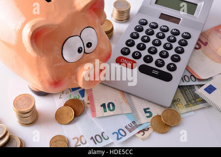 Konzept-Einsparungen und Buchhaltung mit Sparschwein und gestapelten Münzen und Rechnungen und Rechner auf Tisch und weißen Hintergrund. Horizontale Komposition. Elev Stockfoto