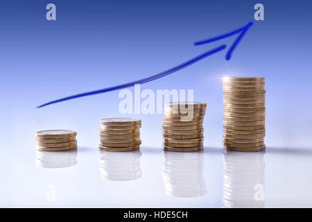 Nach oben Graph des Geschäfts mit Münzen auf weißen reflektierenden Tisch vertreten und Blauton Hintergrund degradiert. Horizontale Komposition. Vorderansicht Stockfoto