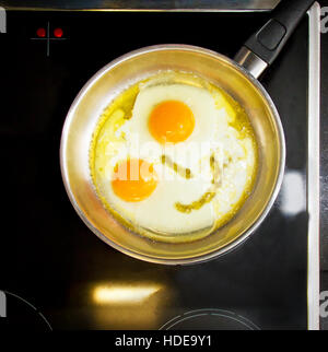 Lächelnd glückliches Gesicht Braten Eiern Frühstück in einer Pfanne Stockfoto