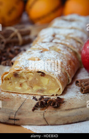 Apfelstrudel mit frischen Äpfeln und Zimt auf einem Holzbrett Stockfoto