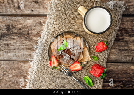 Schokoladen-Fondant mit Erdbeere, Minze und Milch auf dem Holztisch Stockfoto