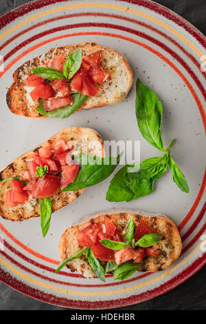 Bruschetta mit Tomaten und Basilikum auf die bunten Keramik-Platte Stockfoto