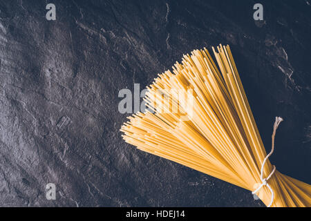 Rohe Spaghetti auf dem schwarzen Stein Hintergrund Draufsicht Stockfoto