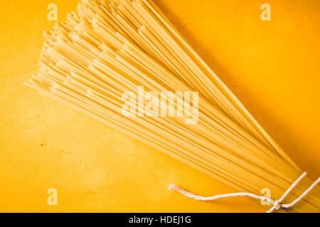 Rohe Spaghetti auf gelbem Hintergrund-Draufsicht Stockfoto