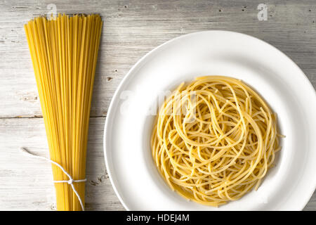 Rohen und gekochten Spaghetti auf dem horizontalen weißen Holztisch Stockfoto