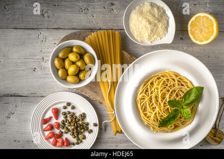 Rohen und gekochten Spaghetti mit verschiedenen Aperitif auf der weißen hölzernen Tischplatte-Ansicht. Konzept der italienischen Küche Stockfoto