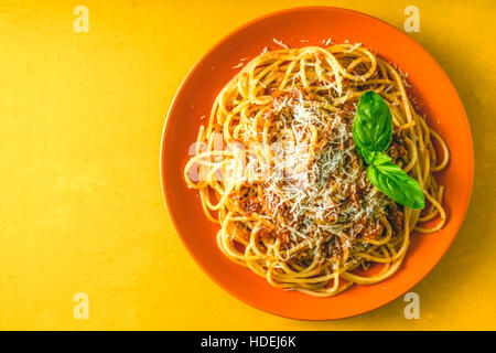 Spaghetti Bolognese auf dem orange Teller auf gelbem Hintergrund-Draufsicht Stockfoto