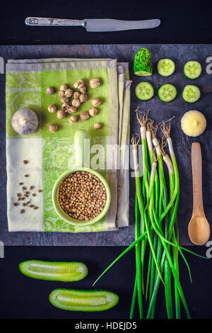 Grünes Gemüse mit Gewürzen auf dem dunklen Stein Hintergrund vertikale Stockfoto