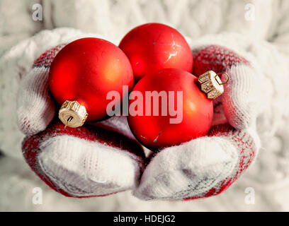 Hände in Handschuhe halten rote Vintage Weihnachten Kugeln Nahaufnahme. Stockfoto