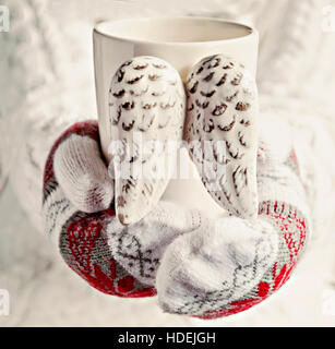Hände in Handschuhe halten einer Tasse Jahrgang Flügel Nahaufnahme. Stockfoto