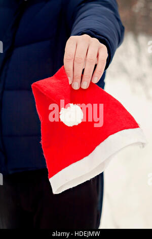 Mannes Hand hält eine Weihnachtsmann-Mütze hautnah. Stockfoto
