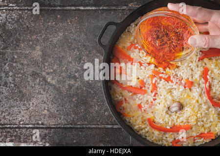 Hinzufügen von Safran in der Pfanne mit Reis und Paprika Draufsicht Stockfoto