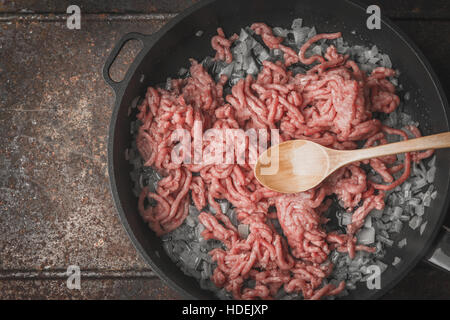 Rohes Hackfleisch mit in Scheiben geschnittenen Zwiebeln in der Pfanne-Draufsicht Stockfoto