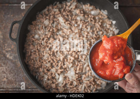 Gehackte Tomaten in die Keramikschale mit unscharfen Topf Draufsicht Stockfoto