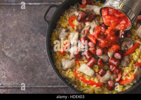 Gehackte Tomaten hinzufügen in der Pfanne mit Kochen Paella Draufsicht Stockfoto