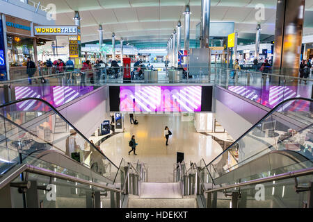 England, London, Heathrow Flughafen, Terminal 2. Departure Lounge Interieur. Fahrtreppen von oberen shopping Niveau zu senken Sitzbereich. Stockfoto