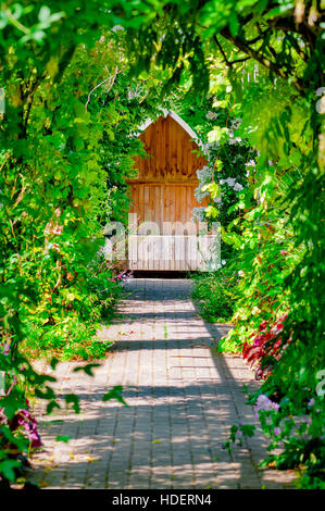 Garten Spalier Gehweg Versteck versteckten ruhigen sitzen Bank Bereich im freien leere umgeben von Reben und Rosen Stockfoto