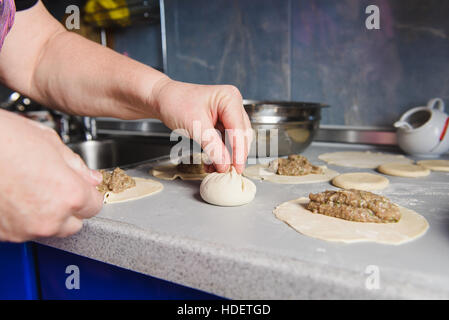 Georgische Küche Khinkali. Ältere Frau bereitet Khinkali. Draufsicht rohen Teig Fleischgericht ungekocht. Stockfoto