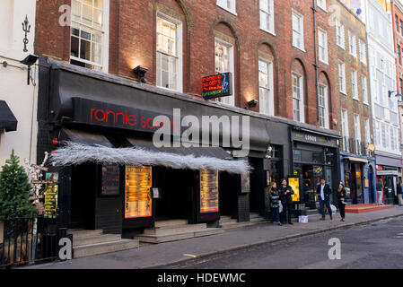 Die Menschen wandern vor Ronnie Scott's Jazz Club in der Frith Street, Soho, London, England, UK. Stockfoto