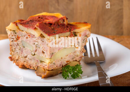 Teil des köstlichen geschichteten Moussaka gekocht für authentisches Rezept mit Fleisch und Kartoffeln auf Teller mit der Gabel gemacht Stockfoto