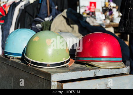 Mehrfarbige Motorradhelme und Nippes auf einem Flohmarkt in London, England, UK Stockfoto