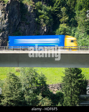 Ein verschwommener LKW fährt über eine Autobahn Brücke der Schweiz Autobahn A2 in Richtung Gotthard-Tunnel durch die Schweizer Alpen. Stockfoto