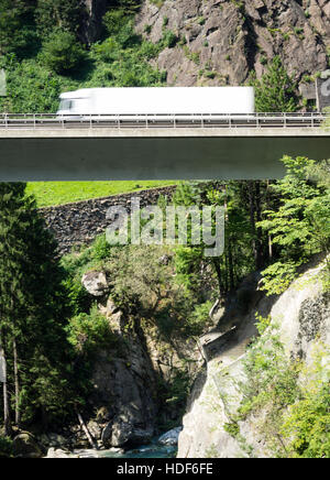 Ein verschwommener LKW fährt über eine Autobahn Brücke der Schweiz Autobahn A2 in Richtung Gotthard-Tunnel durch die Schweizer Alpen. Stockfoto
