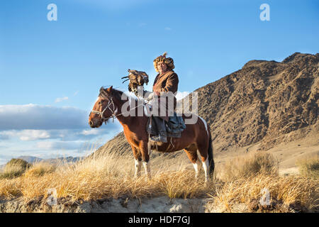 Bayan-Ulgii, Mongolei, 2. Oktober 2015: Alte Adler Jäger mit seinem Altai Steinadler auf seinem Pferd Stockfoto